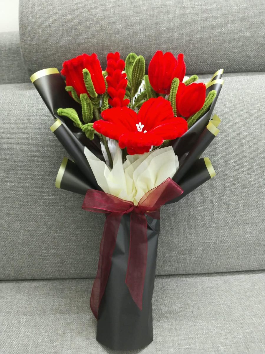 Handmade red tulip and amaryllis bouquet in black wrap with a burgundy ribbon