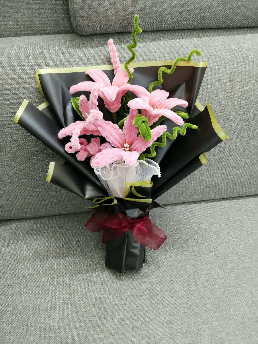 Handmade pink lily bouquet with curled green stems in black wrap